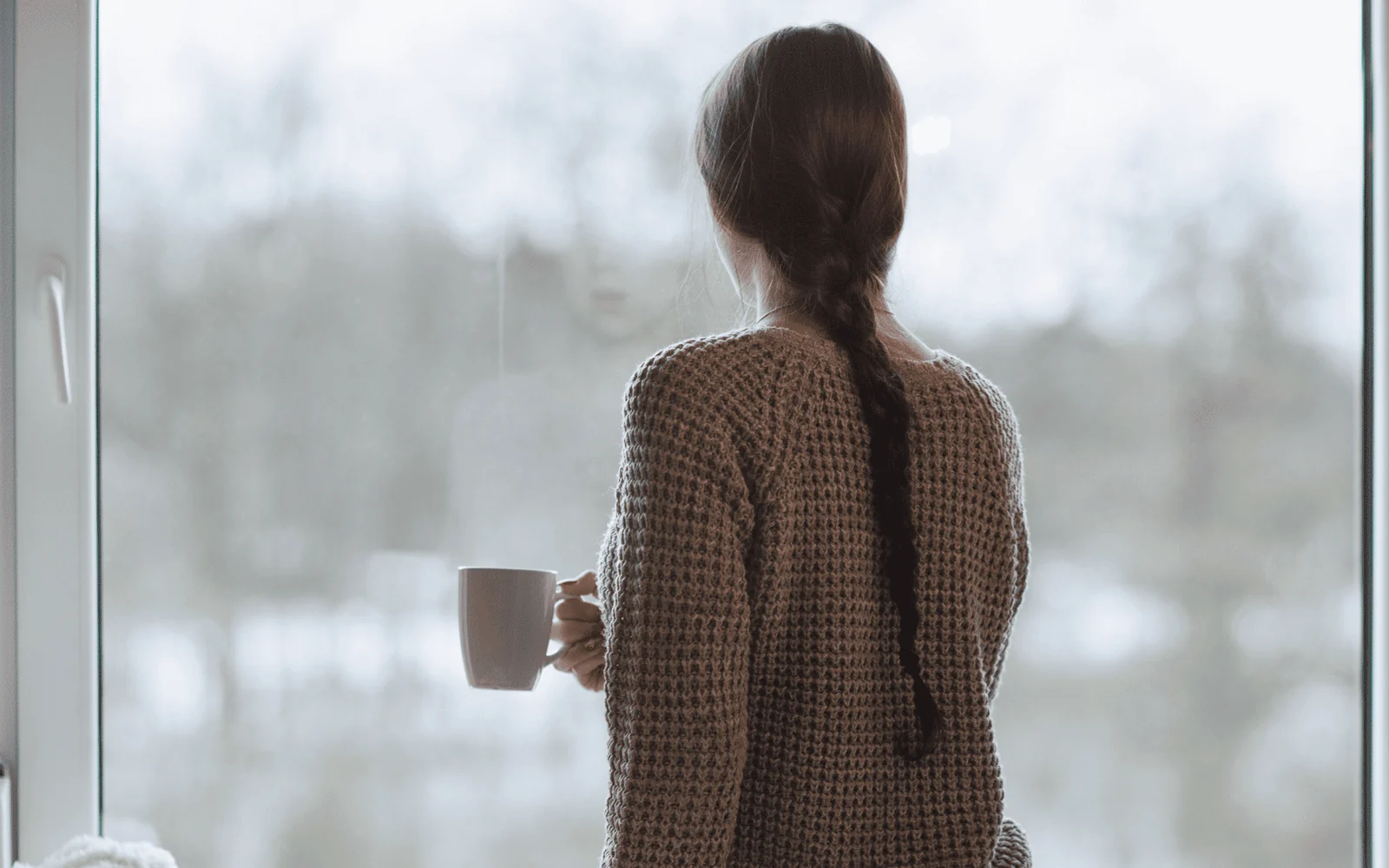 Femme debout face à une fenêtre