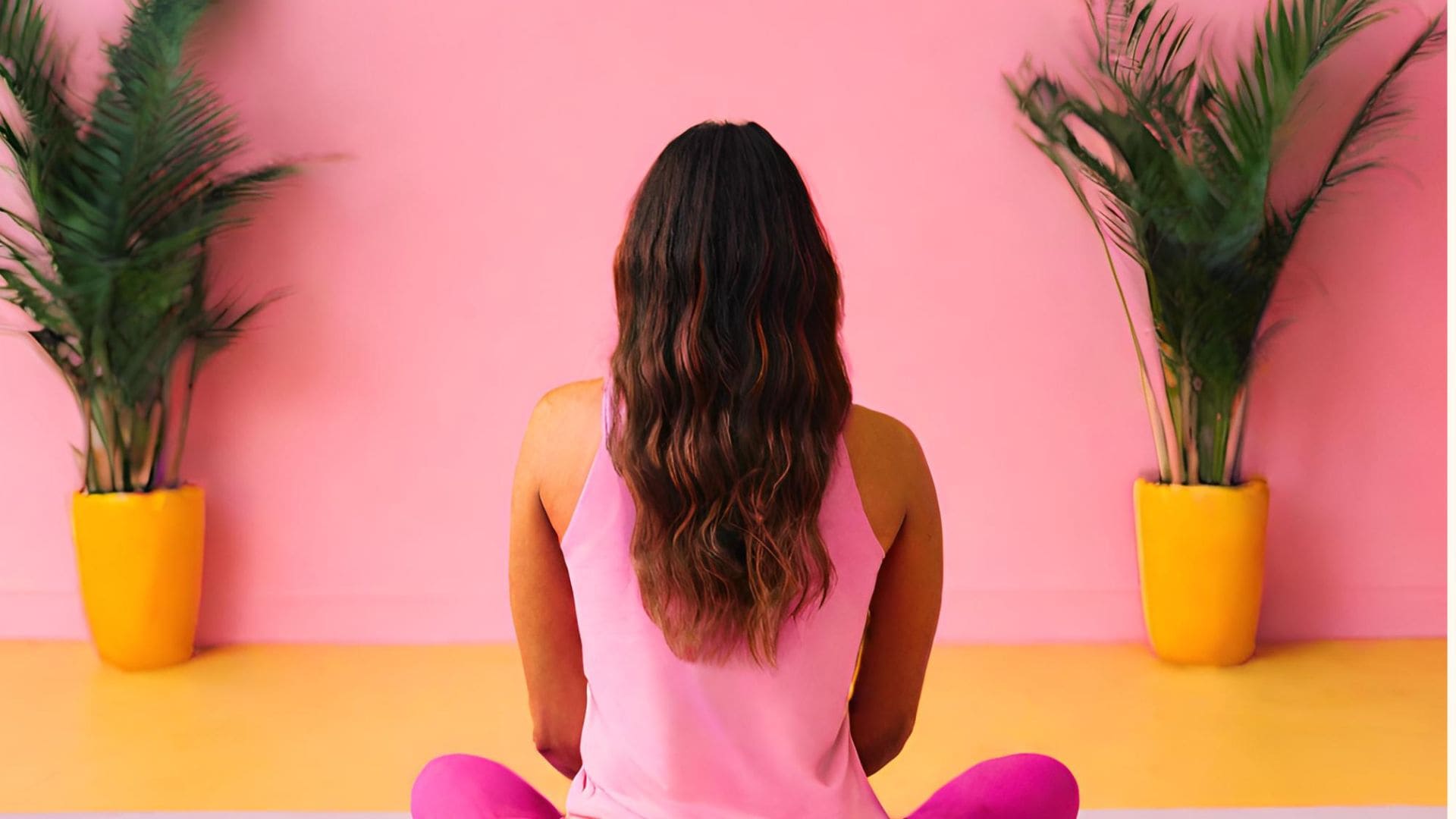 Femme assise de dos dans un décor rose